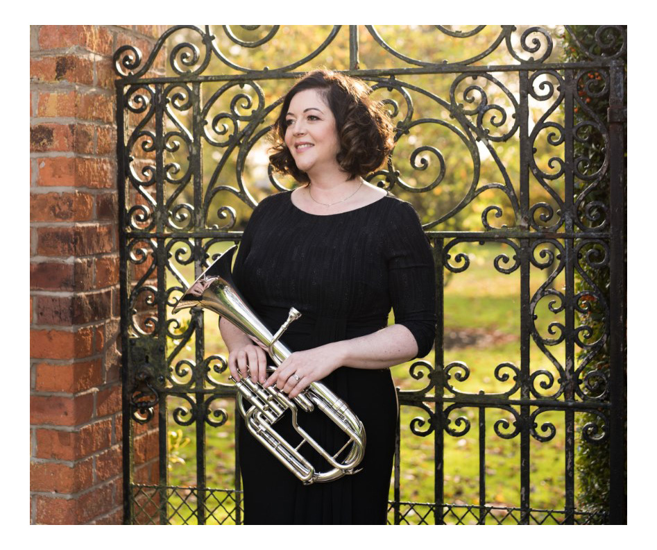 Photo of tenor horn player outside by formal garden gate